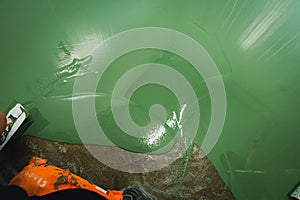 Skilled worker applies green epoxy paint