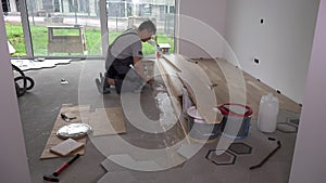 Skilled worker apply glue with trowel on floor for floorboard laying