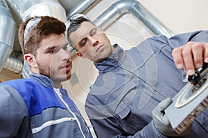 Skilled worker giving instructions to apprentice in factory