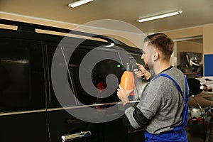 Skilled worker washing tinted car window