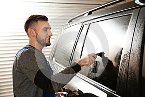 Skilled worker washing tinted car window