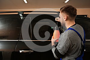 Skilled worker washing tinted car window