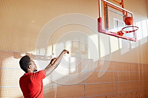 Skilled young basketball player training on court