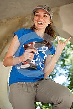 Skilled young female worker is using power screwdriver drilling during construction wooden bench gender equality