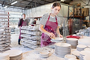 Female ceramicist using sponge to clean pottery plates in workshop photo