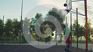 Skillful basketball player taking layup shot at dawn