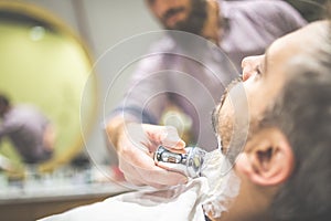 Skillful beautician preparing to shave stubble