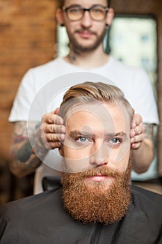 Skillful male barber is serving his client