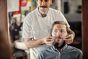 Skillful male barber is serving his client
