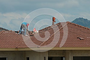 Skillful workers tiling on rooftop of a new house.