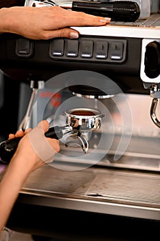 Skillfull barista making coffee in cafe or restaraunt using modern and professional coffee machine
