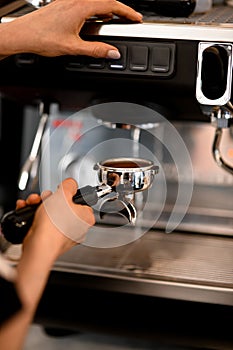 Skillfull barista using coffee machine for making coffee in cafe or restaraunt. Process of preparing espresso.