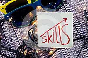 Skills on Sticky note paper with sunglasses on a wooden background with lights concept for selfdevelopment photo