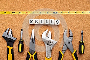 SKILLS word written on wood blocks. Various tools on cork background. business concept