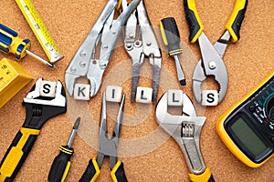 SKILLS word written on wood blocks. Various tools on cork background are holding letter cubes. business concept for skills and