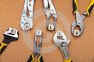 SKILLS word written on wood blocks. Various tools on cork background are holding letter cubes. business concept for skills and