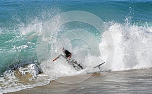 Skim Boarder riding a shore break wave at Aliso Beach in Laguna Beach, California.