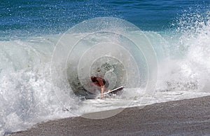 Skim Boarder riding a shore break wave at Aliso Beach in Laguna Beach, California.