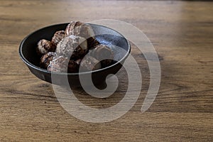 Skin-on boiled taro corm in a black crockery on a wooden table.