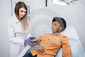 Skin cancer and melanoma prevention. Professional doctor dermatologist examines the patient& x27;s moles on arm of African