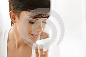 Skin Care. Beautiful Happy Woman Holding Face Cream Lotion