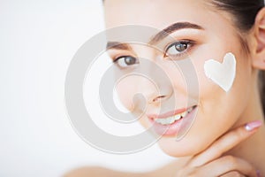 Skin Care. Beautiful model applying cosmetic cream treatment on her face