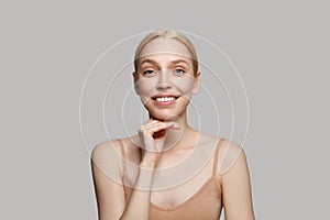 Skin care. Beautiful woman with healthy fresh facial skin touching hands moisturized face skin on light grey background