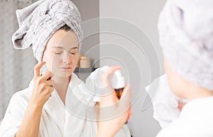 Skin care. Beautiful woman is spraying micellar water on face photo