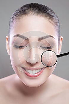 Skin care and beauty concept - face of beautiful young woman with smile over gray background. skin defect on face by loupe.