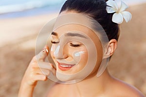 Skin care. Beauty Concept. Young pretty woman applying sun cream  and touch own face