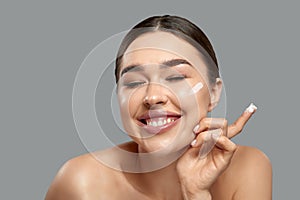 Skin care. Beauty Concept. Young woman holding cosmetic moisturizing cream. Portrait of girl face with clean healthy skin.