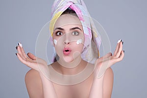 Skin care. Beauty portrait of a beautiful woman applying face cream isolated on studio background. Young spa model uses