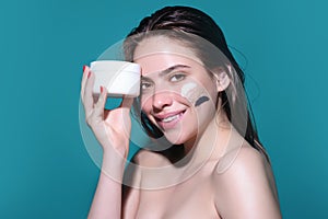 Skin care. Beauty portrait of a beautiful woman applying face cream isolated on studio background. Young spa model uses