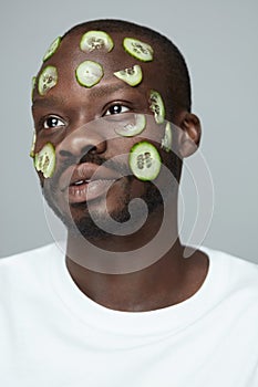 Skin Care. Beauty Treatment. Cucumber Mask. African Male Model Doing Facecare Routine. photo