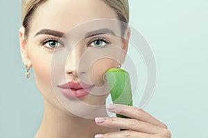 Skin care. Beauty Woman with perfect skin holding fresh leaf of Aloe Vera. Portrait of Beautiful Blonde Spa Girl with perfect skin