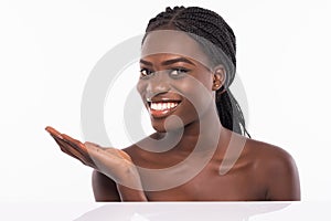 Skin care beauty woman showing empty palm with copy space for product. Excited and very fresh smiling African emale beauty model