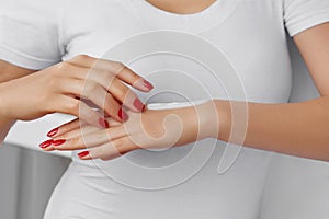 Skin Care Concept. Beautiful Woman With Hand Cream, Lotion On Her Hands. Close Up Photo of Female Hands with Red Manicure Applying