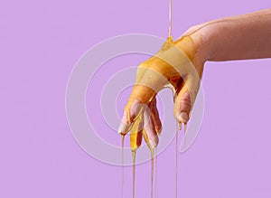 Skin care concept, pouring honey over hand,  on a purple background