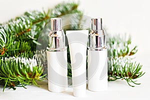 Skin care cosmetics bottles on a fir branches background. Blank containers on a wooden white background. Christmas present for wom