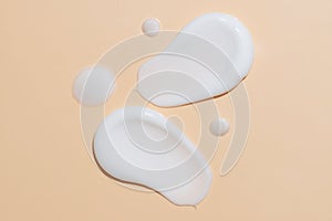 Skin care cream, face serum, lotion swatch smear on beige background. White light creamy cosmetic beauty product smudge