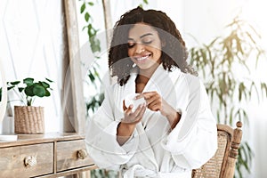 Skin Care Cream. Smiling African American Woman Holding Jar With Hydrating Lotion