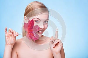 Skin care. Face of young woman girl with red maple leaf.