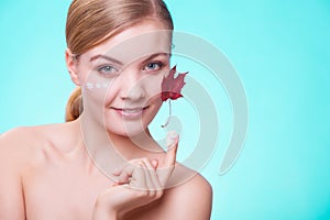 Skin care. Face of young woman girl with red maple leaf.
