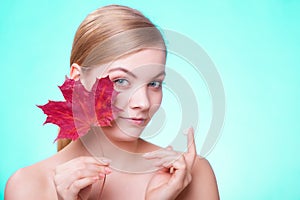 Skin care. Face of young woman girl with red maple leaf.