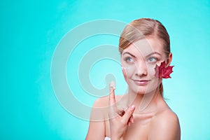 Skin care. Face of young woman girl with red maple leaf.