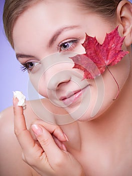 Skin care. Face of young woman girl with red maple leaf.