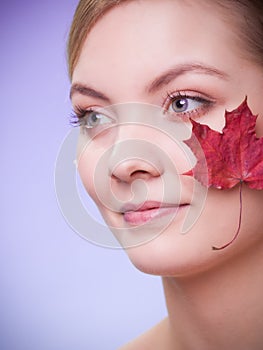 Skin care. Face of young woman girl with red maple leaf.