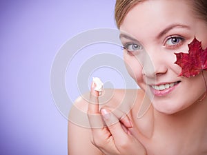 Skin care. Face of young woman girl with red maple leaf.