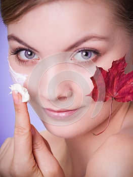 Skin care. Face of young woman girl with red maple leaf.