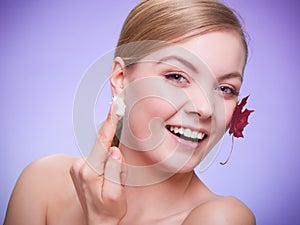 Skin care. Face of young woman girl with red maple leaf.